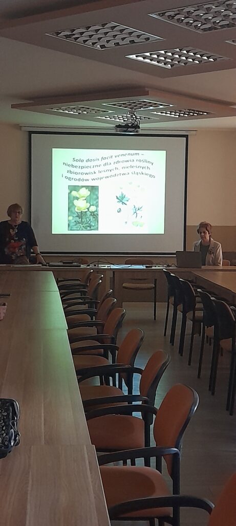 Prezes Julia Dziwoki i prelegentka Barbara Majchrzak na tle prezentacji multimedialnej.